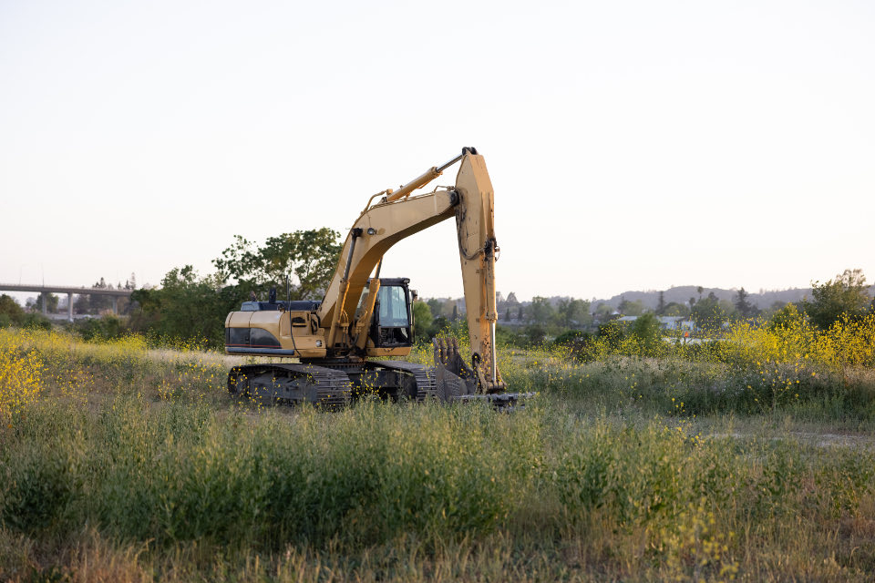 Bagger steht auf einer freien, mit Gras bewachsenen Fläche