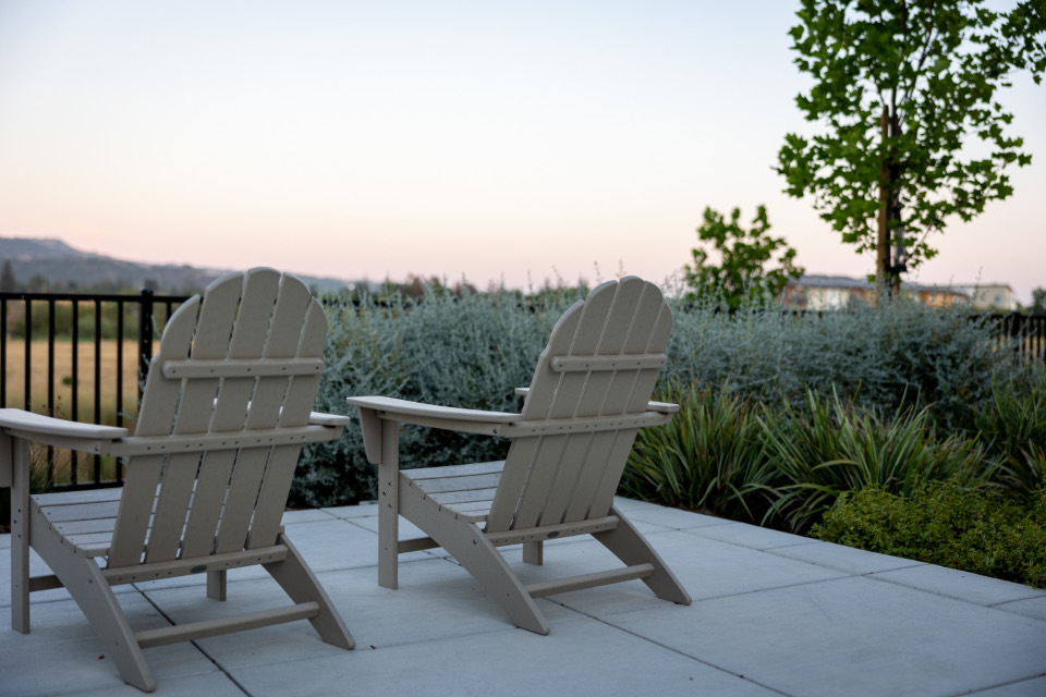 Zwei leere Gartenstühle auf einer Terrasse in der Abenddämmerung
